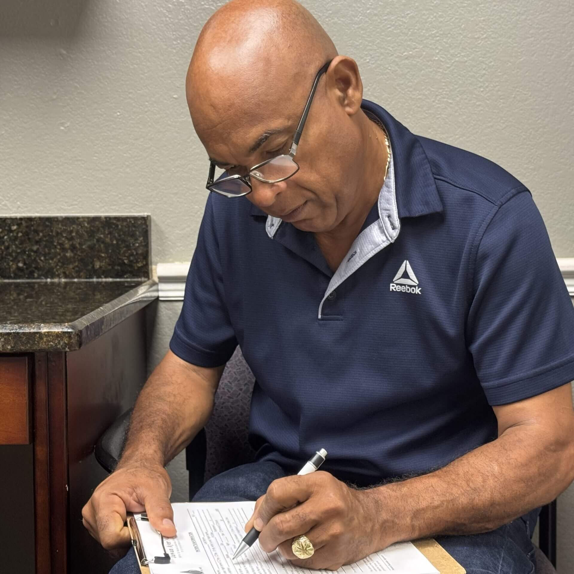 Man writing on clipboard in an office.